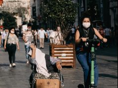 man in black t-shirt and blue denim jeans sitting on brown wooden bench